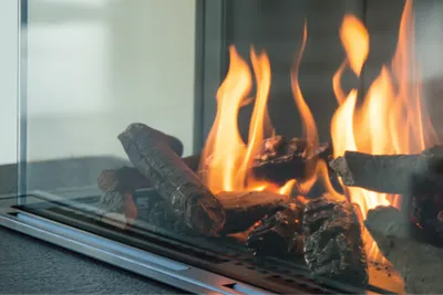 Flames and logs in a gas fire behind glass.