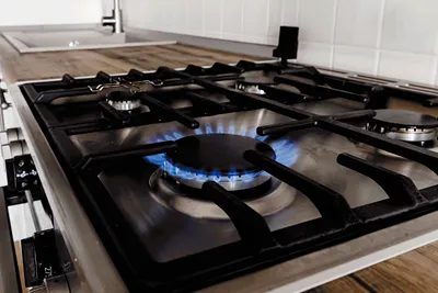 A lit gas hob burner with a clear blue flame.